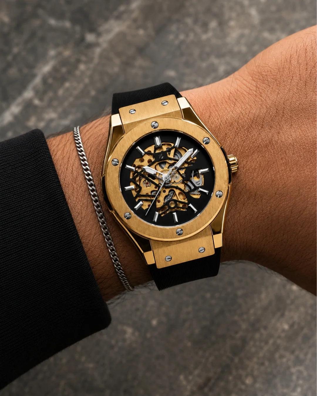 Image of William Corbier MACH Imperial Gold men's automatic skeleton watch, worn on a wrist with a silver chain bracelet on a city street