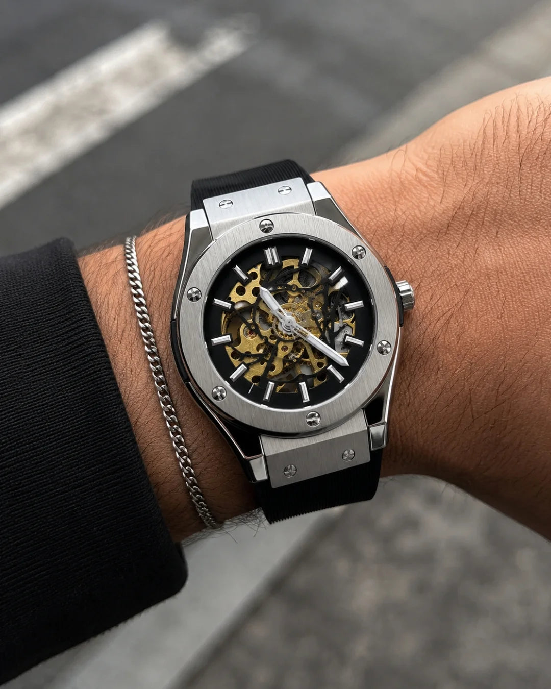 William Corbier MACH Silver Mist men's automatic skeleton watch, worn on a wrist with a silver chain bracelet on a city street