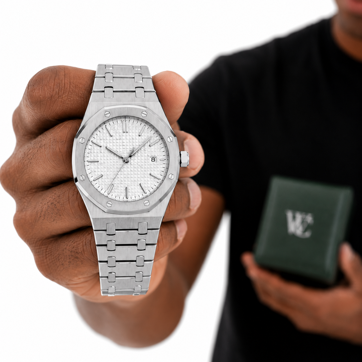 Image of Man holding a William Corbier RIDGE Alpine white dial steel watch towards the camera beside a green gift box