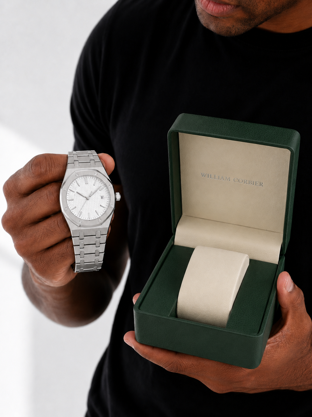 Image of Man in a black t-shirt showing the watch beside an open green gift box wearing the William Corbier RIDGE Alpine men's white dial steel watch