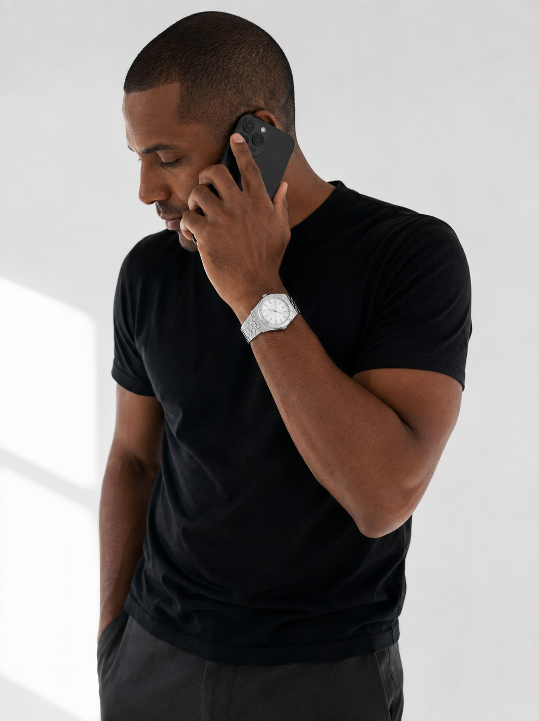 Image of Man in a black t-shirt on a phone call wearing the William Corbier RIDGE Alpine men's white dial steel watch