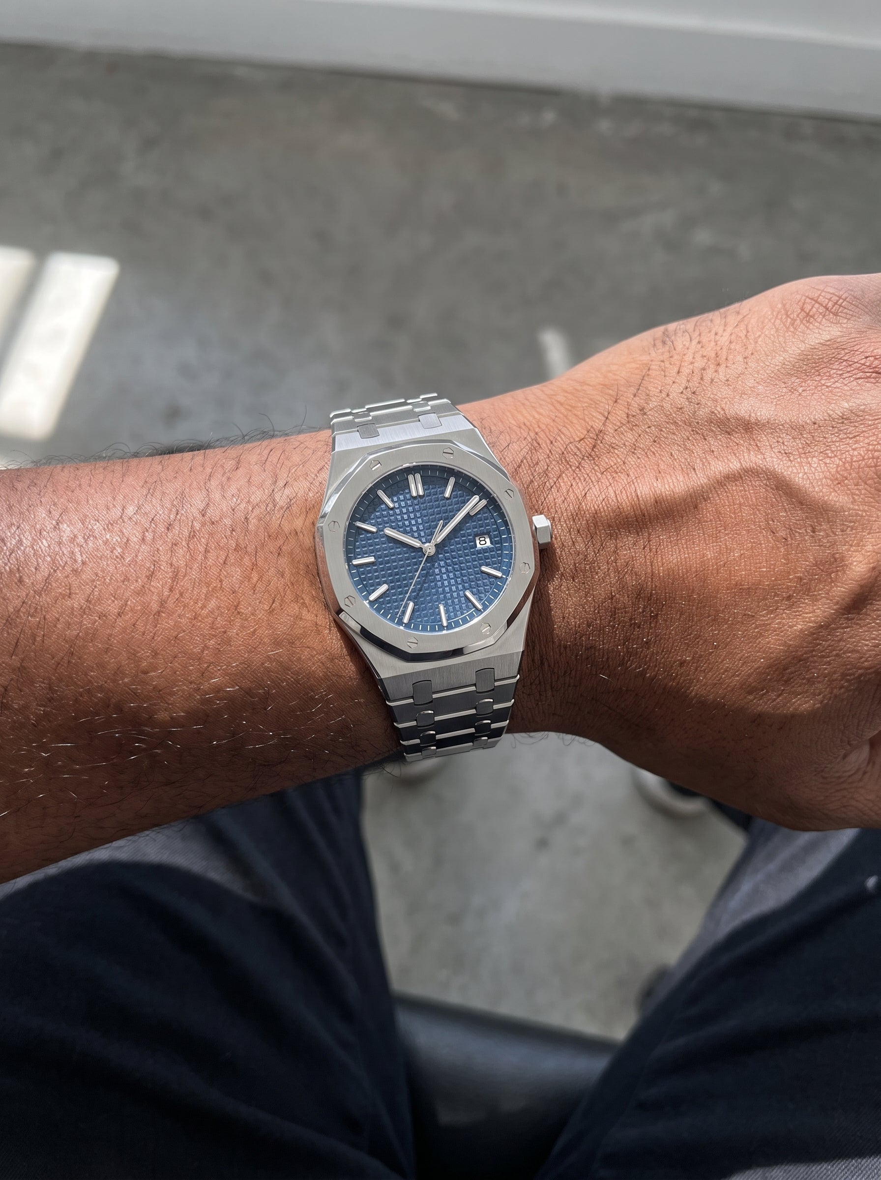 Image of William Corbier RIDGE Dark Azure men's blue dial steel watch, worn on a wrist resting on a lap