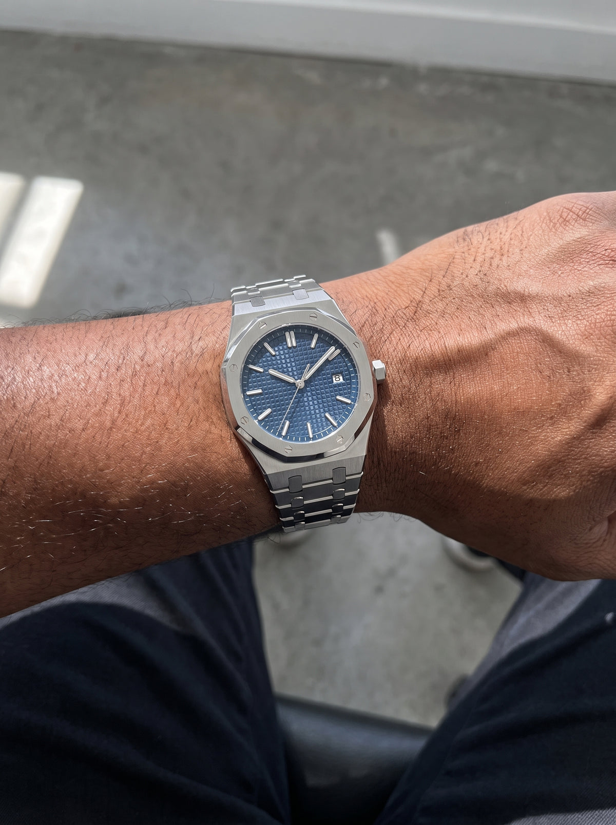 William Corbier RIDGE Dark Azure men's blue dial steel watch, worn on a wrist resting on a lap