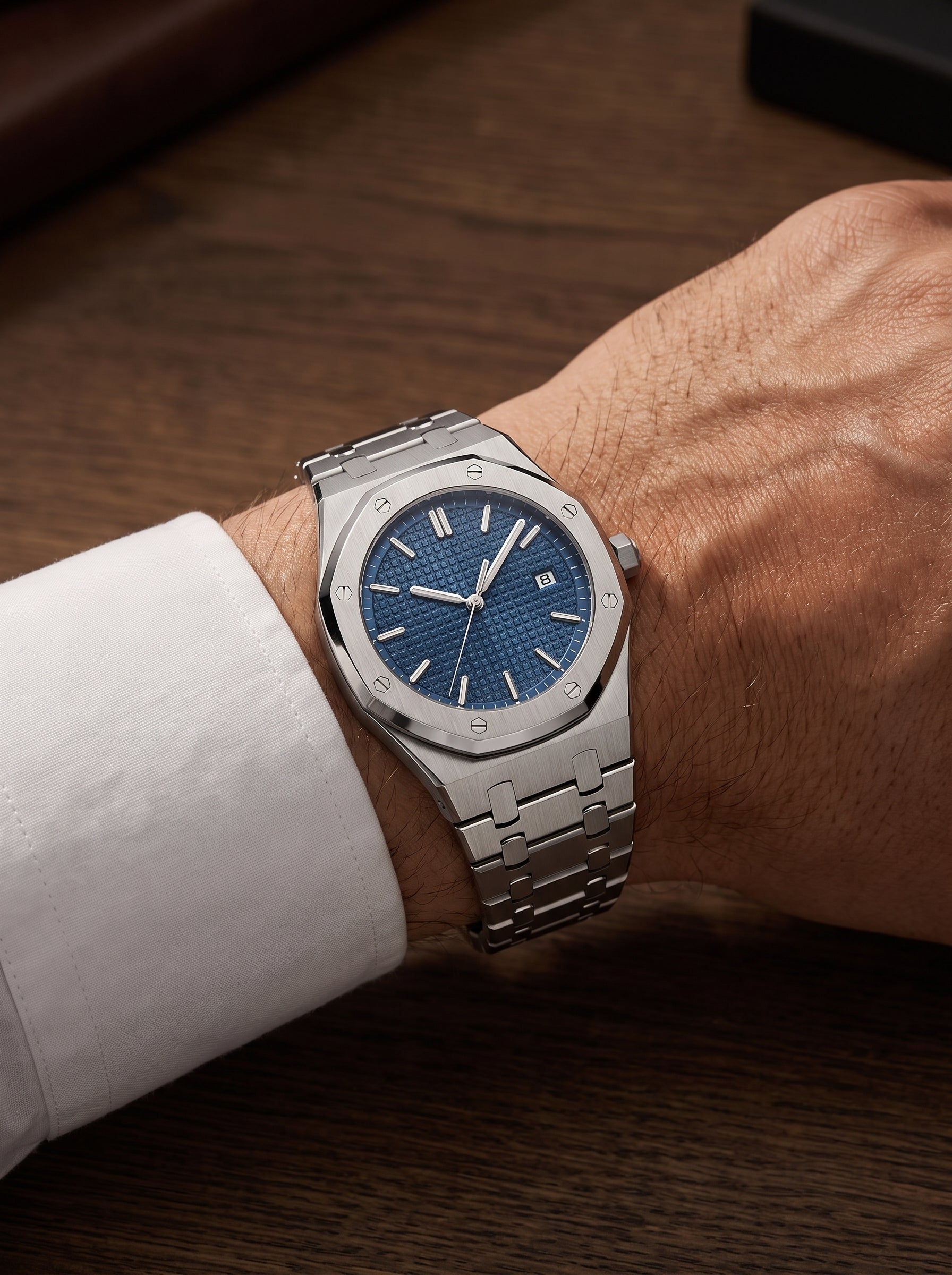 Image of William Corbier RIDGE Dark Azure men's blue dial steel watch, worn on a wrist with a white shirt cuff at a wooden desk