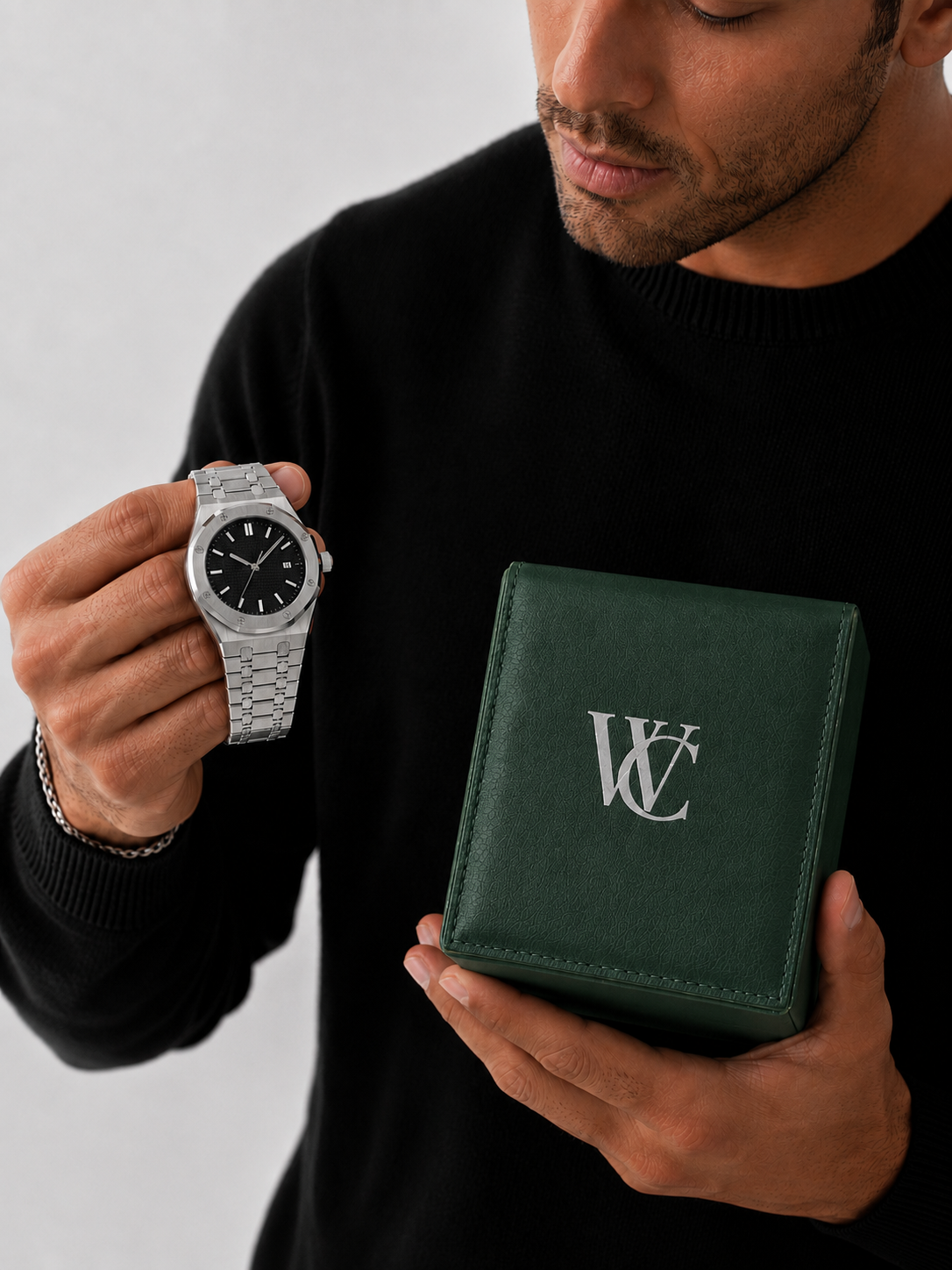 Image of Man in a black sweater holding the watch beside a green gift box wearing the William Corbier RIDGE Obsidian men's black dial steel watch