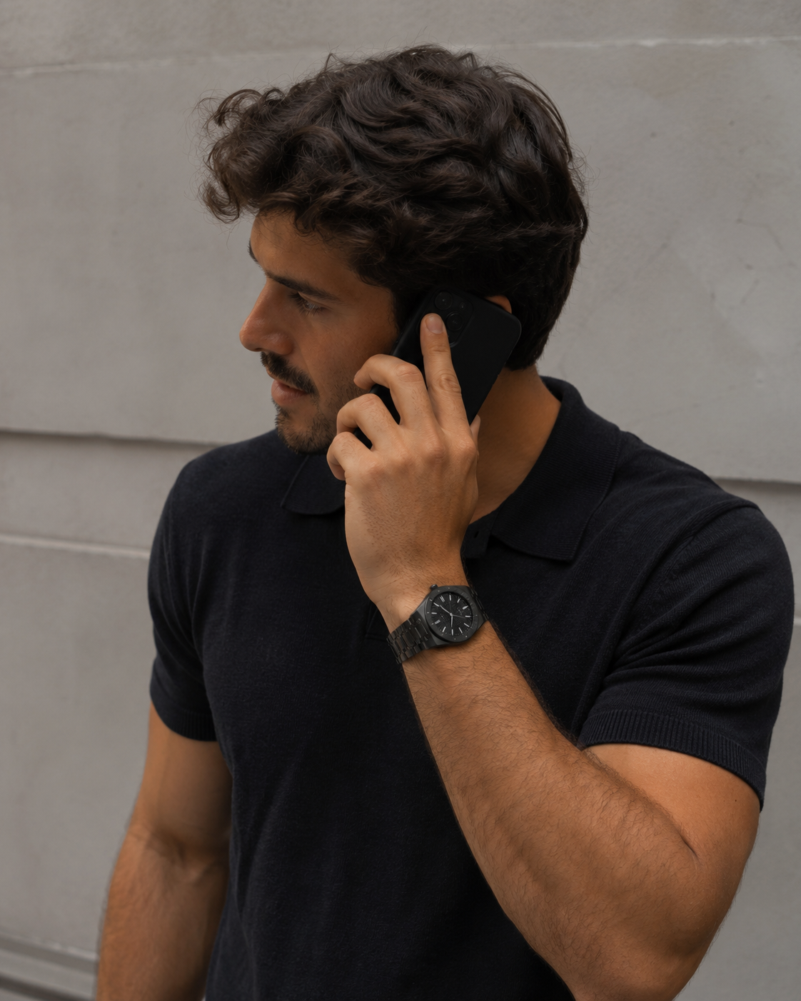 Man in a navy polo on a phone call wearing the William Corbier RIDGE Onyx men's black dial steel watch