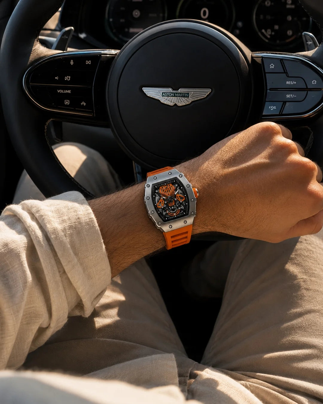 William Corbier SURGE Ember men's automatic skeleton watch with an orange strap worn on a wrist at a steering wheel